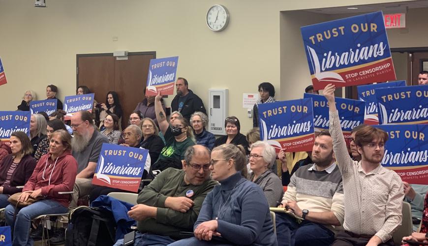Residents hold up signs saying "Trust Our Librarians" at a library board meeting in Lafayette, LA.